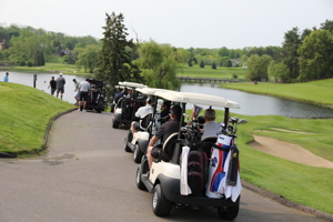 People in golf carts driving on a golf course.