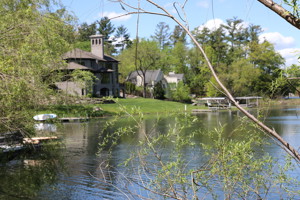 A house on a lake that is pictured through trees at a distance.