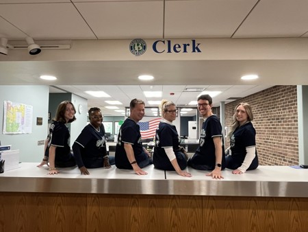 Clerk's Office staff sitting on counter facing away from camera but heads turned towards camera.