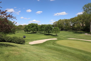 View of a golf course with a golf cart on it.